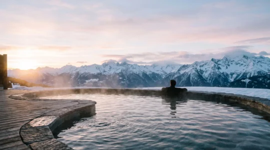 Bassin extérieur d'un spa de montagne français avec vue panoramique sur les sommets enneigés