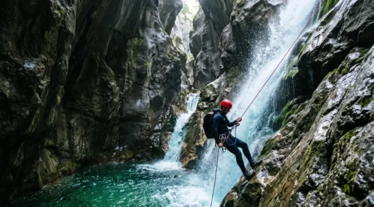 Un pratiquant de canyoning descend en rappel une cascade dans une gorge française entourée de roche calcaire et de végétation méditerranéenne